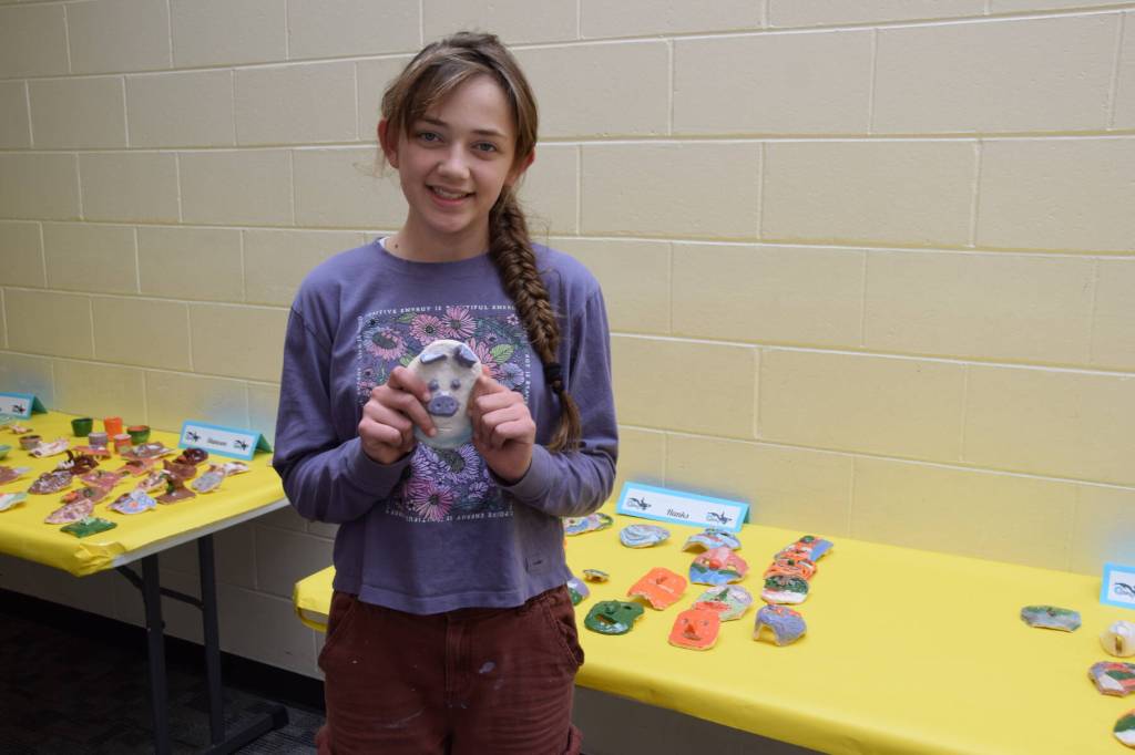 Margaret Gricius stands holding one of her ceramic art pieces, showcased during the annual Arts Extravaganza at West Homer Elementary School on Friday, May 2, 2025, in Homer, Alaska. (Chloe Pleznac/Homer News)