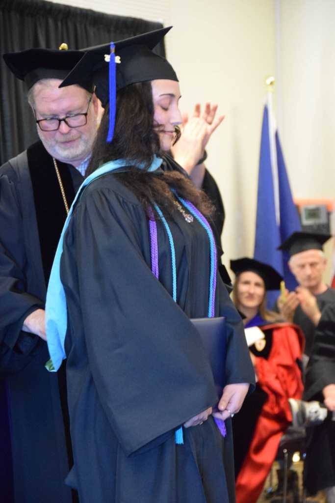 Homer News reporter Chloe Pleznac receives her hood for her Masters in Public Administration degree at the 55th annual commencement ceremony on Wednesday, May 7, 2025, at Kachemak Bay Campus in Homer, Alaska. (Delcenia Cosman/Homer News)