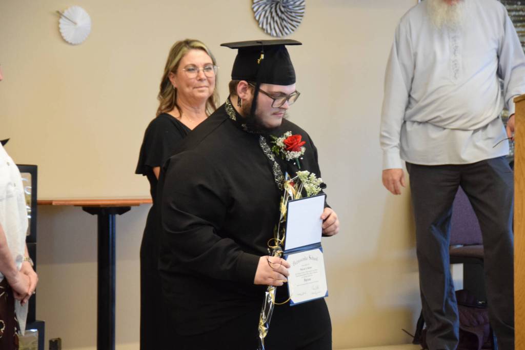 Kiprian Reutov holds up his diploma during the Voznesenka School commencement ceremony held Monday, May 19, 2025, at Lands End Resort in Homer, Alaska. (Delcenia Cosman/Homer News)