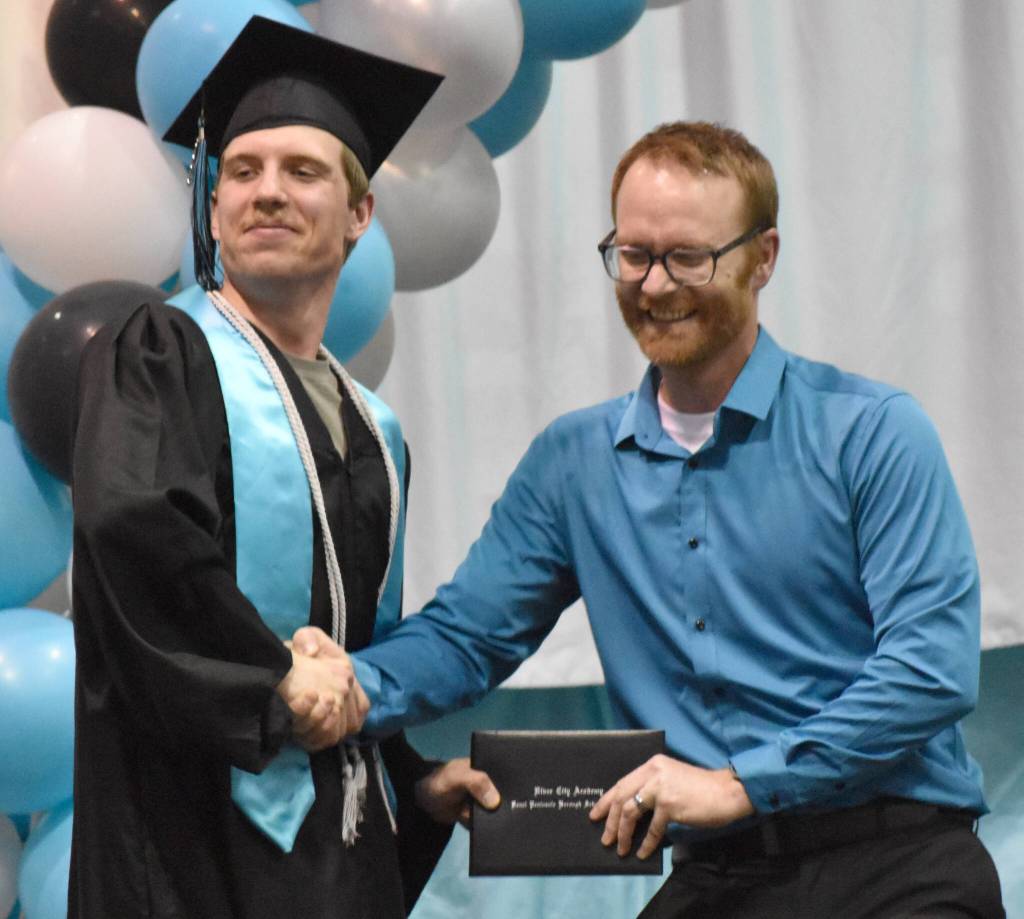 Nicholaus Benkendorf takes command in a grip-strength contest with Principal Shea Nash during the awarding of diplomas at the River City Academy graduation ceremony Tuesday, May 20, 2025, at Skyview Middle School just outside of Soldotna, Alaska. (Photo by Jeff Helminiak/Peninsula Clarion)