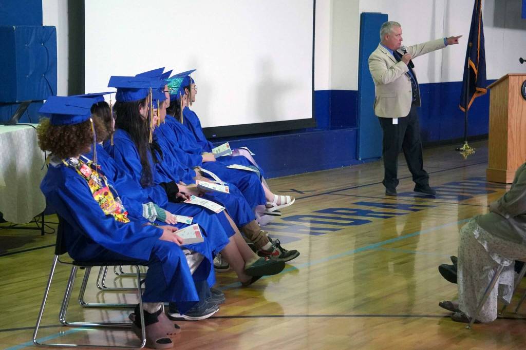 Kenai Alternative High School graduates listen to a speech by Principal John Galahan during their commencement ceremony in the schools gym in Kenai, Alaska, on Wednesday, May 22, 2025. (Jake Dye/Peninsula Clarion)