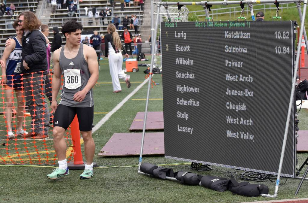 Ketchikans Jason Lorig looks at the results of the 100-meter dash while Soldotna assistant Joe Shirley congratulates Tyce Escott in the background Saturday, May 31, 2025, at the Division I state track meet at Dimond High School in Anchorage, Alaska. Escotts time was later adjusted to 10.83 seconds. (Photo by Jeff Helminiak/Peninsula Clarion)