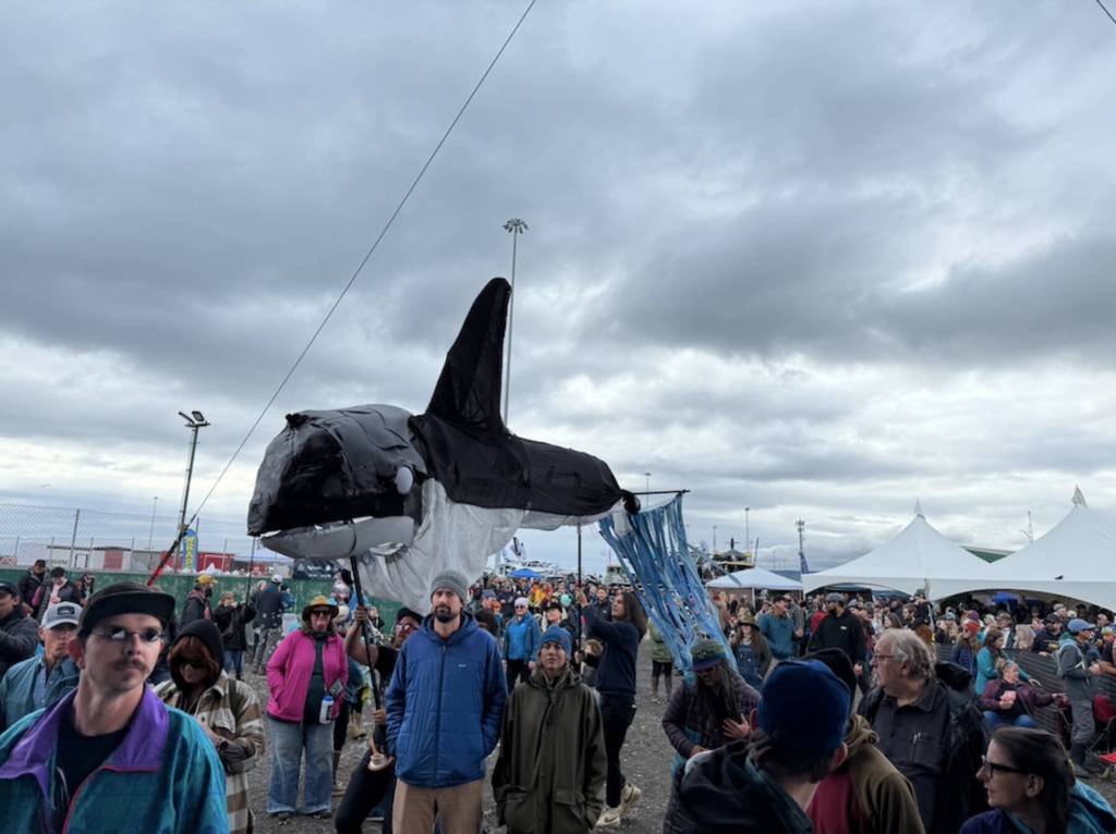 A large, creeping orca puppet enters the crowd during the Black Barrel & The Bad Men performance at the inaugural HomerFest on the Homer Spit on Saturday. (Chloe Pleznac/Homer News)