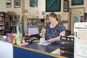 Anchor Point Library director Deanna Thomas works the front counter on Friday, June 6, 2025, in Anchor Point, Alaska. (Delcenia Cosman/Homer News)