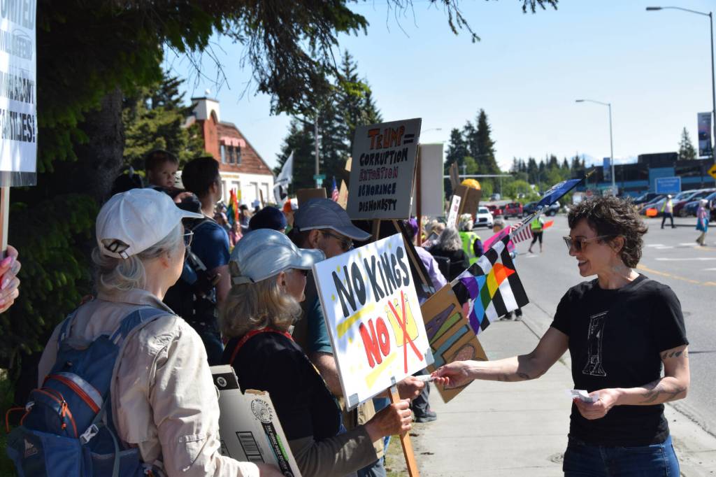 Susannah Webster hands out informational cards to demonstrators on Saturday, June 14, 2025, at the No Kings demonstration in Homer, Alaska. (Chloe Pleznac/Homer News)