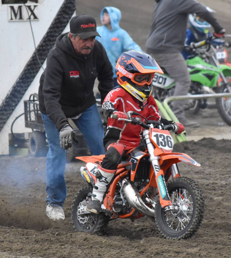 Rick Bailey of Ninilchik helps his grandson, Clydon Meyer, get started in 50 novice at the Alaska State Motocross Series Race 4 on Sunday, June 15, 2025, at Twin City Raceway in Kenai, Alaska. (Photo by Jeff Helminiak/Peninsula Clarion)