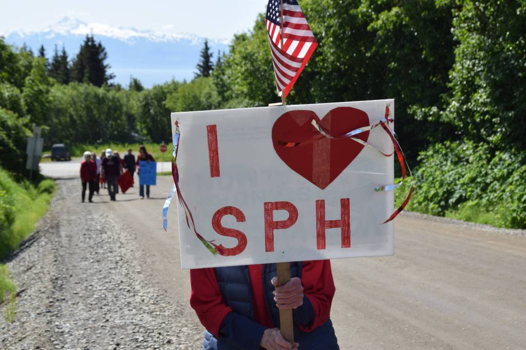 A woman stands with her sign held up during a rally in support of Medicaid and South Peninsula Hospital on Wednesday, June 18. (Chloe Pleznac/Homer News)