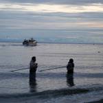 Fishers stand at the mouth of the Kasilof River in Kasilof, Alaska, early in the morning of the first day of the Kasilof River personal use sockeye salmon dipnet fishery on Wednesday, June 25, 2025. (Jake Dye/Peninsula Clarion)