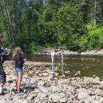Community members watch ducks float by on the Anchor River during the annual Anchor River Duck Races on Saturday, July 5, 2025, in Anchor Point, Alaska. (Delcenia Cosman/Homer News)