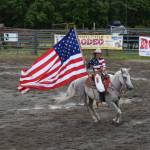 Haylee Overson circles the arena with the Alaska flag on Sunday, July 6, 2025 at the Kenai Peninsula Fairgrounds in Ninilchik, Alaska. (Chloe Pleznac/Homer News)