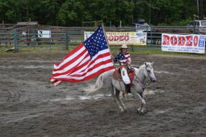 Haylee Overson circles the arena with the Alaska flag on Sunday, July 6, 2025 at the Kenai Peninsula Fairgrounds in Ninilchik, Alaska. (Chloe Pleznac/Homer News)