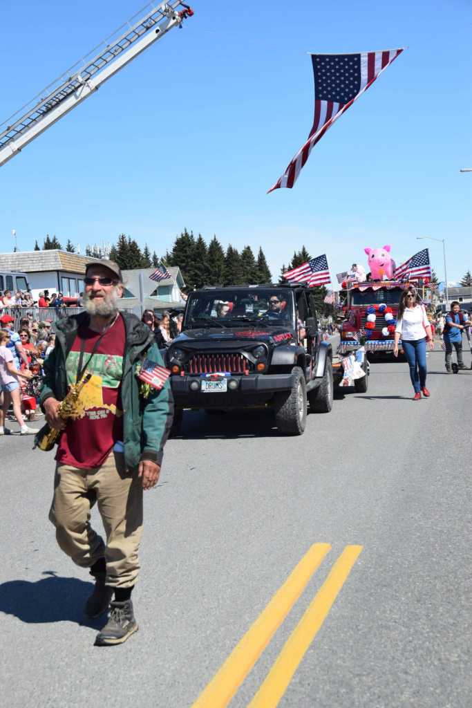 A large American flag is upheld by the Homer Volunteer Fire Department and Kachemak Emergency Services ladder trucks over the Fourth of July parade procession on Friday, July 4, 2025, in Homer, Alaska. (Delcenia Cosman/Homer News)