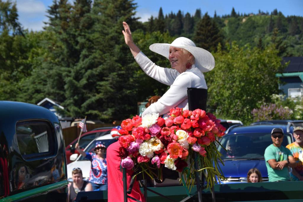 Rita Jo Schoultz, owner of Alaska Perfect Peony, waves to the crowds along Pioneer Avenue during the Fourth of July parade on Friday, July 4, 2025, in Homer, Alaska. Schoultz was honored as this years parade Grand Marshal, as the Fourth of July celebration coincided with Homers sixth annual Peony Celebration. (Delcenia Cosman/Homer News)