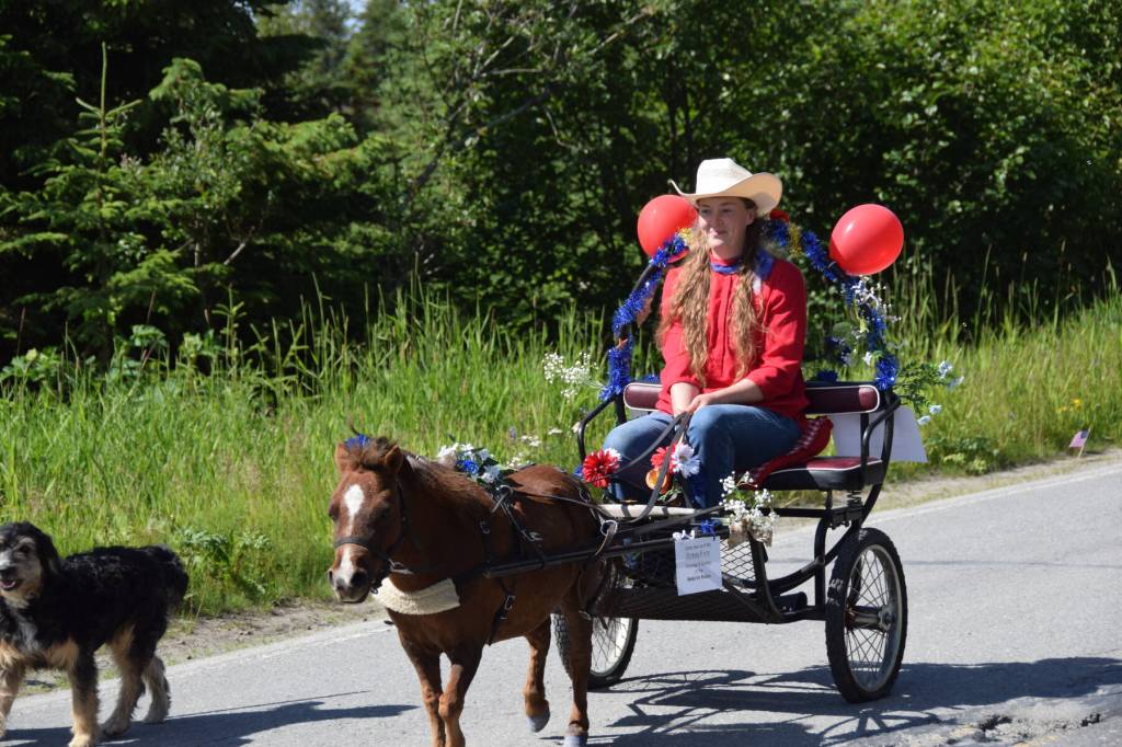 A rodeo participant drives a cart pulled bya toy pony down Milo Fritz Avenue during the Fourth of July parade on Friday, July 4, 2025, in Anchor Point, Alaska. (Delcenia Cosman/Homer News)