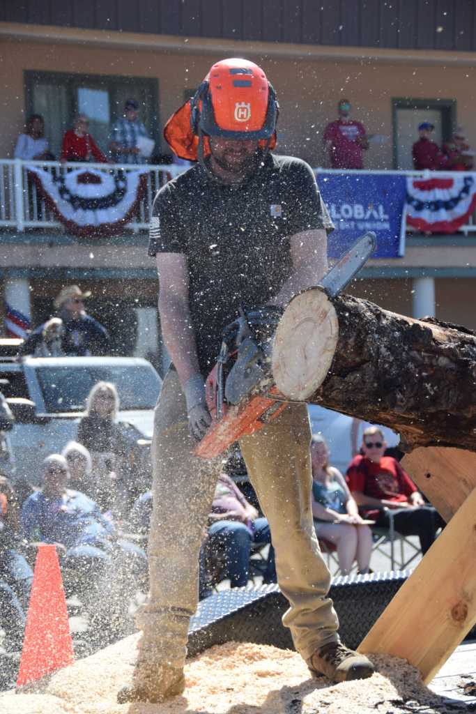 A Rooted Tree Service employee cuts sections off a spruce log during the Fourth of July parade on Friday, July 4, 2025, in Homer, Alaska. (Delcenia Cosman/Homer News)