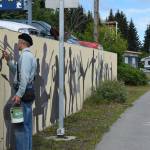 Artist Tom Reed begins to paint the silhouette of musician David Webster on July 2, 2025 in Homer, Alaska. Reed added 10 artists to the wall over the last few weeks, marking the end of the art project he began in 1985. (Chloe Pleznac/Homer News)