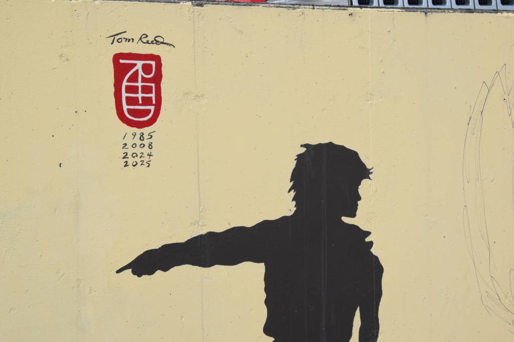 The iconic child silhouette points to the line of artists on Tom Reeds mural in Homer, Alaska on July 2. (Chloe Pleznac/Homer News)