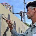 Artist Tom Reed begins to paint the silhouette of musician David Webster on July 2, 2025 in Homer, Alaska. Reed added 10 artists to the wall over the last few weeks, marking the end of the art project he began in 1985. (Chloe Pleznac/Homer News)