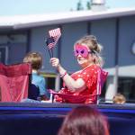 A masked woman waves a small American flag during a Fourth of July parade on South Willow Street in Kenai, Alaska, on July 4, 2025. (Photo courtesy Sarah Every)