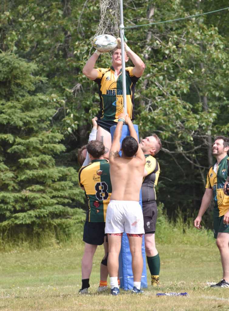 Ben Richards of Fairbanks, in a jersey for the Kenai River Wolfpack, gets a ball out of a dipnet with help from other Kenai players at the Kenai Dipnet Fest Rugby 10s Tournament at Kenais Millennium Square on Saturday, July 19, 2025. (Photo by Jeff Helminiak/Peninsula Clarion)