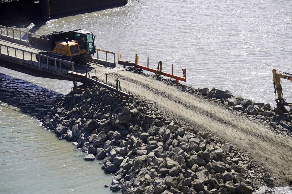 Armor rock from Sand Point is offloaded from a barge in the Kenai River in Kenai, Alaska, part of ongoing construction efforts for the Kenai River Bluff Stabilization Project on Wednesday, July 23, 2025. (Jake Dye/Peninsula Clarion)