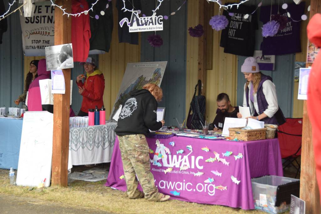 Salmonfest attendees visit advocacy booths in the Causeway, including the Abused Womens Aid in Crisis, Inc., on Saturday, Aug. 2, 2025, at the Kenai Peninsula Fairgrounds in Ninilchik, Alaska. (Delcenia Cosman/Homer News)