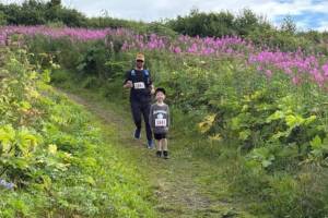 Kyle Settles and Jack Settles run along the trail at Eveline State Recreation Site on Saturday, Aug. 9, 2025, during the inaugeral 5K hosted by Kachemak Bay Running Club. (Photo courtesy of Michael Murray)