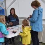 A patron speaks to youth vendors at their Homer Farmers Market booth during Kids' Vending Day on Wednesday, Aug. 13, 2025, in Homer, Alaska. (Delcenia Cosman/Homer News)