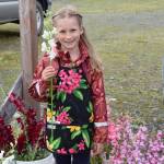 Avery Rennolds holds up one of her snapdragon stems she had for sale on Kids Vending Day on Wednesday, Aug. 13, 2025, at the Homer Farmers Market in Homer, Alaska. (Delcenia Cosman/Homer News)