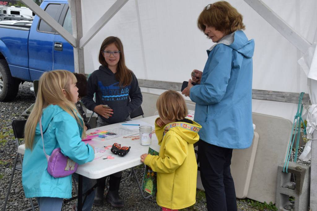 A patron speaks to youth vendors at their Homer Farmers Market booth during Kids Vending Day on Wednesday, Aug. 13, 2025, in Homer, Alaska. (Delcenia Cosman/Homer News)