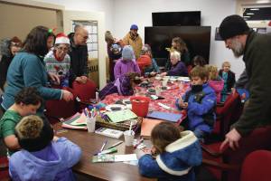Kids and parents craft holiday ornaments during at the Homer Chamber of Commerce and Visitor Center during their annual Christmas tree lighting celebration on Thursday, Dec. 5, 2024, in Homer, Alaska. (Delcenia Cosman/Homer News)