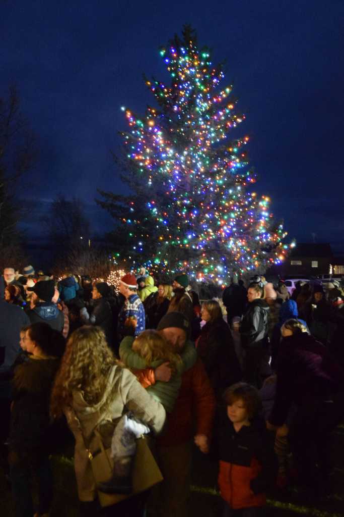 Families and community members attending the annual holiday tree lighting ceremony cheer as the large Christmas tree is lit on Thursday, Dec. 4, 2025, at the Homer Chamber of Commerce and Visitor Center in Homer, Alaska. (Delcenia Cosman/Homer News)