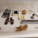 Items from the Pratt Museums permanent collection, including a berry scoop, wrapped bark and woven baskets, model mukluks, a postal letter scale, model dog sled, harpoon head and more, are displayed alongside the Homer High School Alaska History classs exhibit on Friday, Dec. 5, 2025, in the museums downstairs classroom in Homer, Alaska. (Delcenia Cosman/Homer News)