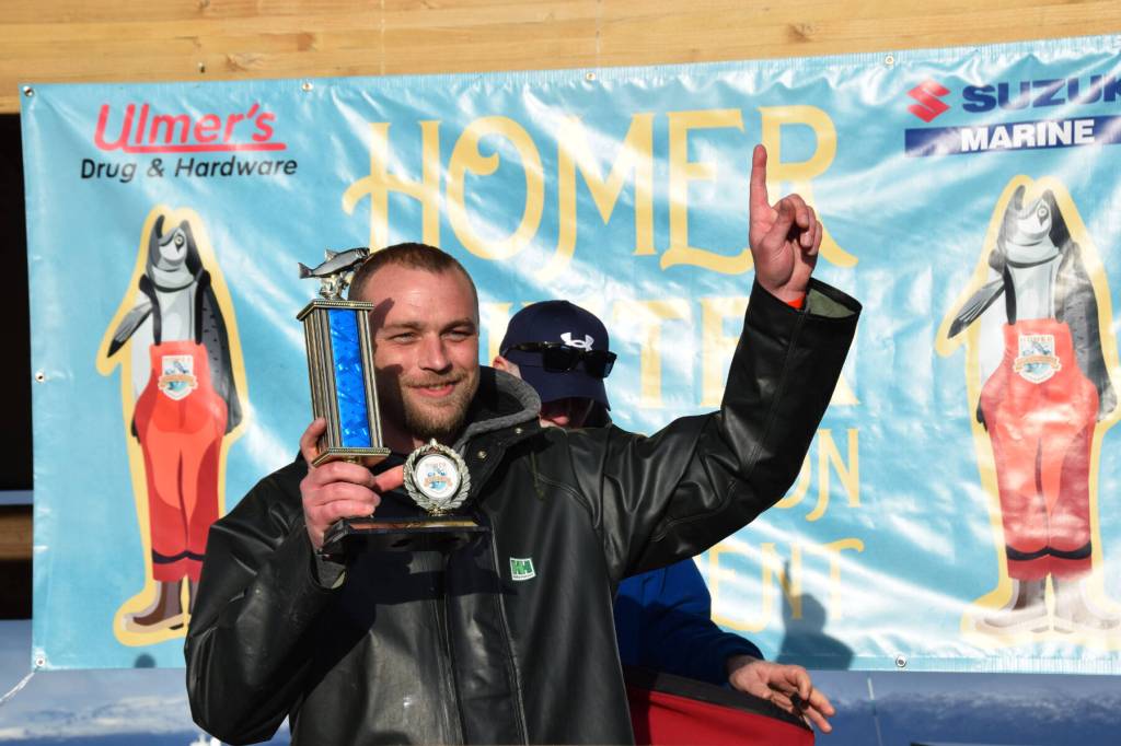 Delcenia Cosman/Homer News 
Tournament champion Zach Weimann holds up his first-place trophy during the 2025 Homer Winter King Salmon Tournament on Saturday, March 22, 2025, at the Deep Water Dock on the Homer Spit<ins> in Homer, Alaska</ins>.