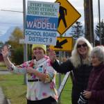 Delcenia Cosman/Homer News 
Ash-Lee Waddell (left), candidate for the District 9 seat on the Kenai Peninsula Borough School District Board of Education, holds a campaign sign and waves with supporters to passersby along the Sterling Highway<ins> in Homer, Alaska</ins>, on Election Day, Tuesday, Oct. 7, 2025.