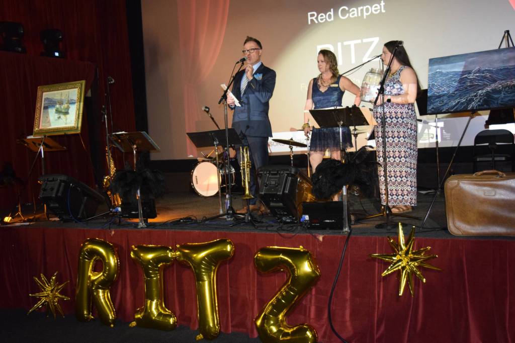 (from left to right) Jim Anderson, serving as master of ceremonies, announces the winners of the quilt raffle alongside Pratt Museum board member Kate McGregor and board treasurer Jennifer Bartolowits during the Pratt Museums Red Carpet Ritz fundraiser on Saturday, Oct. 4, 2025, at the Porcupine Theater<ins>in Homer, </ins><ins>Alaska</ins>. (Delcenia Cosman/Homer News)