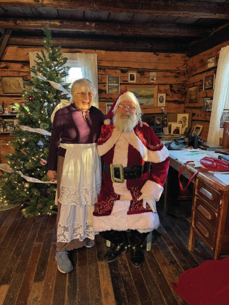 Photo provided by Whitney Harness 
Milli Martin (left), the Homer Society of Natural History, Inc. Board Vice President, and Santa George Cutting III pose for a photo in the Pratt Museum Harrington Cabin on Saturday, Dec. 13, 2025.