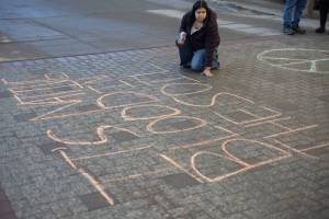 Macelle Joseph, a member of the Juneau-Douglas High School: Yadaa.at Kalé chapter of Alaska Youth for Environmental Action, writes Its Native blood in the soil, not your oil outside the Alaska State Capitol building on Jan. 24<ins>, 2026</ins>. Dozens of Juneauites participated in the student-led protest against the LNG pipeline.