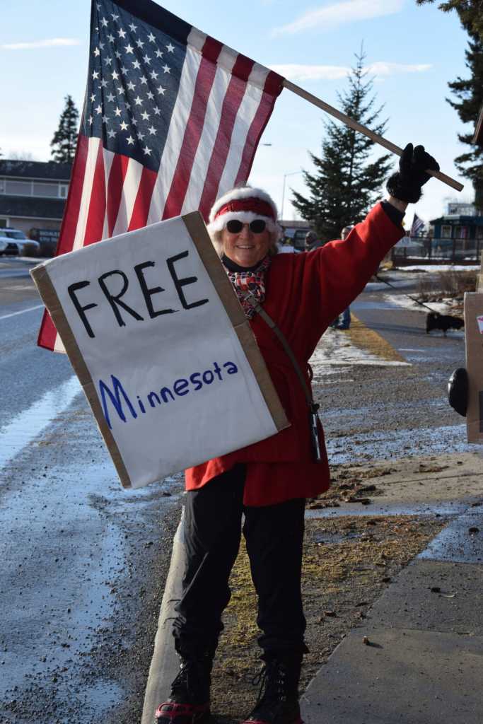 Poppy Benson carries an American flag and a Free Minnesota sign during the ICE OUT demonstration on Sunday, Feb. 1, 2026, at WKFL Park in Homer, Alaska. (Delcenia Cosman/Homer News)