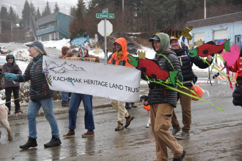Members of the Kachemak Heritage Land Trust walk down Pioneer Avenue carrying cardboard king salmon and other props at the Winter Carnival Parade on Saturday, Feb. 14, 2026, in Homer, Alaska. (Delcenia Cosman/Homer News)