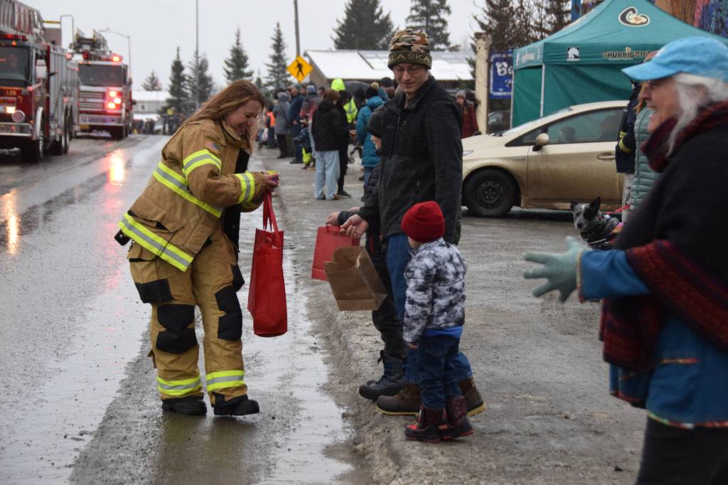 A member of the Homer Volunteer Fire Department hands out candy to young spectators at the Winter Carnival Parade on Saturday, Feb. 14, 2026, in Homer, Alaska. (Delcenia Cosman/Homer News)