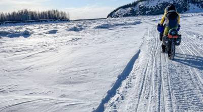 Forest Wagner rides his fat bike near Bishop Rock, right, a pinch point on the flow of the Yukon River, on April 5, 2026.