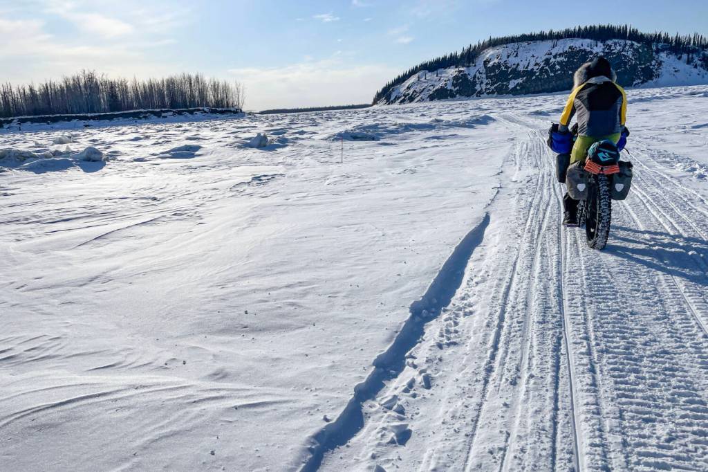 Forest Wagner rides his fat bike near Bishop Rock, right, a pinch point on the flow of the Yukon River, on April 5, 2026.