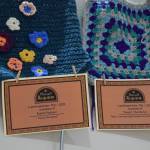 Memorial certificates are displayed with framing squares created by local fiber arts on a memory wall, part of the Mozart Requiem performance on Friday, May 1, 2026, in Homer, Alaska. (Delcenia Cosman/Homer News)