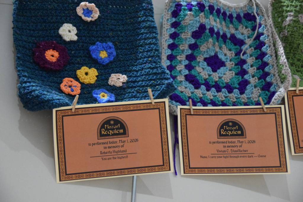 Memorial certificates are displayed with framing squares created by local fiber arts on a memory wall, part of the Mozart Requiem performance on Friday, May 1, 2026, in Homer, Alaska. (Delcenia Cosman/Homer News)