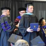 Casey Fetterhoff graduates with his masters degree and is hooded by University of Alaska Regent Joe Crum and University of Alaska Anchorage Vice-Chancellor Aaron Dotson during a commencement ceremony held Wednesday, May 6<ins>, 2026,</ins> at Kachemak Bay Campus<ins> in Homer, Alaska</ins>. (Delcenia Cosman/Homer News)