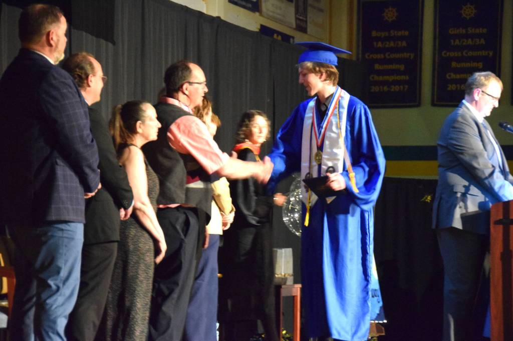 Homer High School Class of 2026 valedictorian Lukas Renner (center) shakes hands with Kenai Peninsula Borough School District representatives as he receives his diploma in a commencement ceremony on Monday, May 18<ins>,</ins> <ins>2026</ins>, in the Homer High School Alice Witte Gymnasium<ins> in Homer, </ins><ins>Alaska</ins>. (Delcenia Cosman/Homer News)