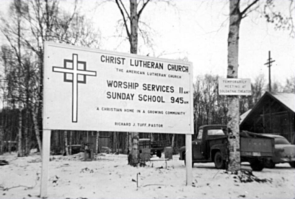 Photo from the Kenai Peninsula College photo archive
Signs of the times at Soldotnas Lutheran Church, which was still under construction in the early 1960s. The small sign on the birch tree reads, Temporarily Meeting at Soldatna Theater.