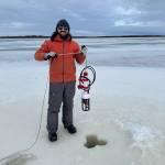 Eli Gomez deploys a mooring through the ice on the Kuskokwim River in winter 2025 to measure water levels, temperature, salinity and currents. (Photo by Steve Dykstra)